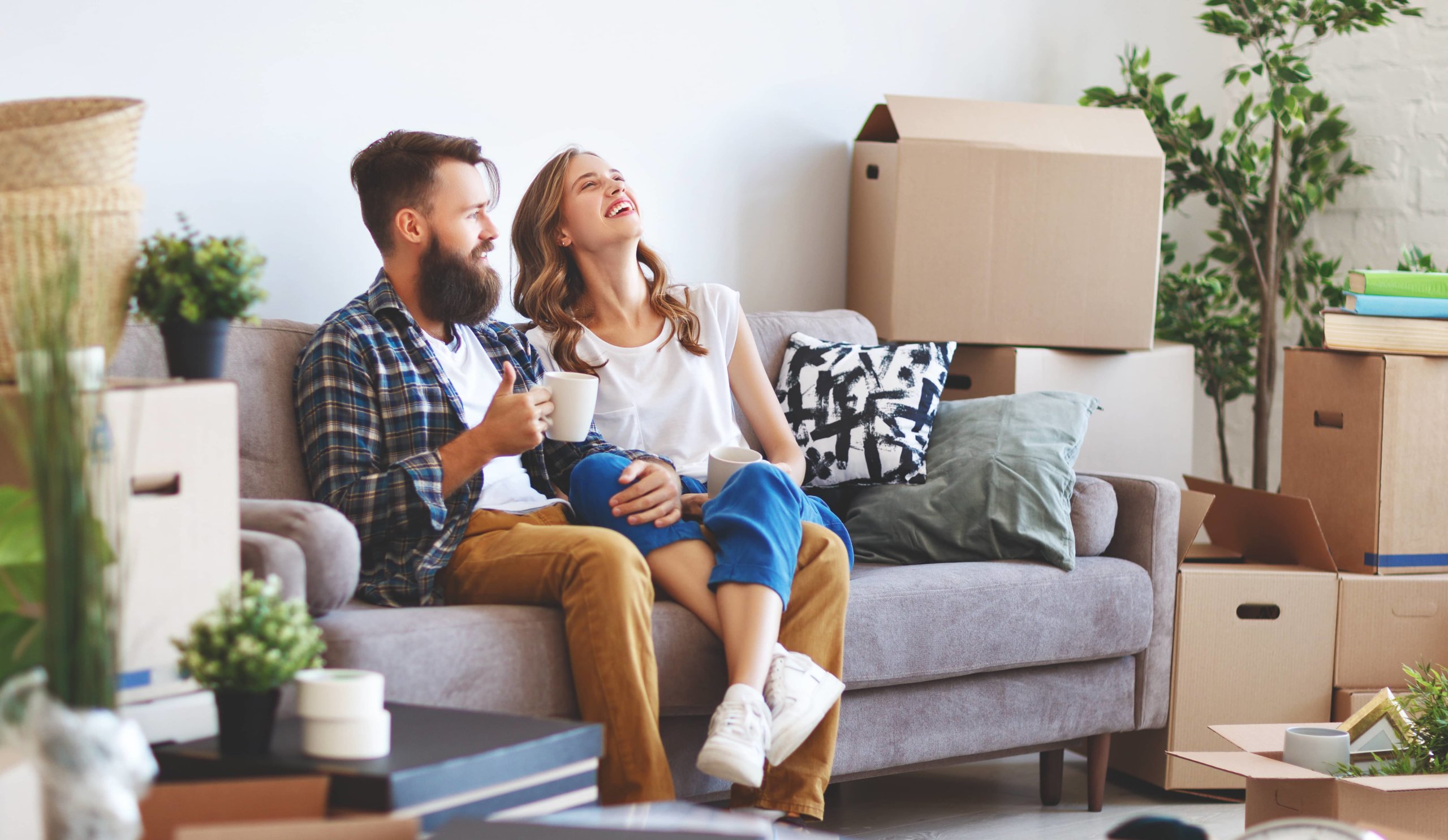 Your couple sitting on the couch in their new home surrounded by boxes that need to be unpacked.