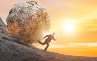 Man running away from a large ball of money rolling downhill.