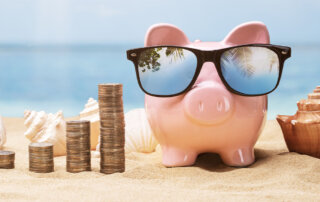 Retired piggy bank on the beach with sunglasses on.