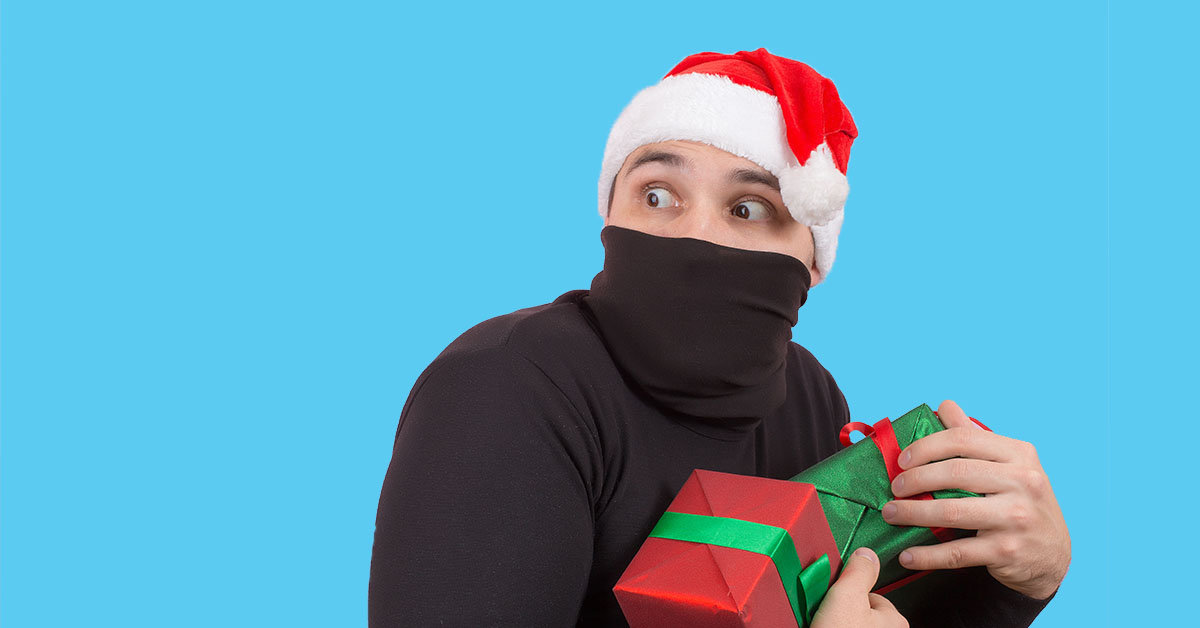 Man dressed in black wearing a santa hat while stealing gifts..