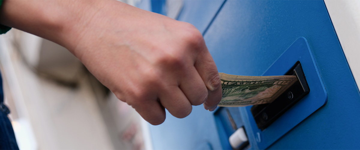 Close up of a human taking money out of an ATM machine.
