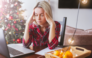 Frustrated woman in Christmas pajamas taking a break from her laptop.